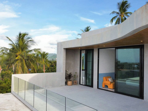 Contemporary villa architecture with glass doors opening toward lush tropical scenery.