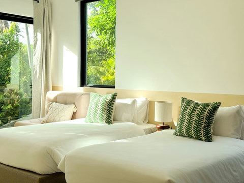 Bright and stylish bedroom with soft bedding, tropical accents, and peaceful garden views.