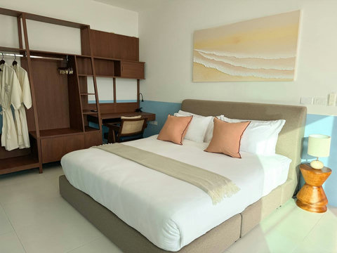 Main bedroom featuring a plush bed with crisp linens, warm terracotta accents, and a dedicated workspace desk for remote travelers.