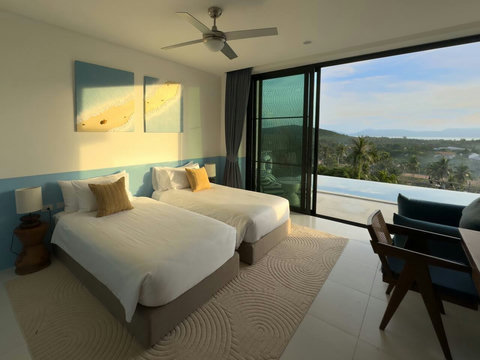 Sun-drenched bedroom with twin beds opening directly to a private balcony. Step outside for fresh air and stunning views.