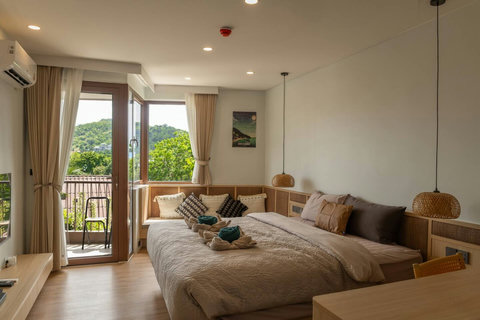 Studio layout with balcony chair, dining table and comfortable queen bed
