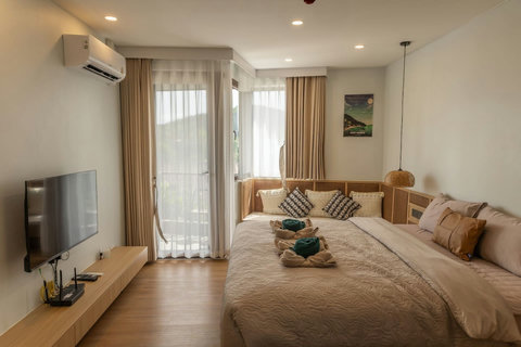 Warm studio bedroom with sheer drapes and a wall-mounted Smart TV