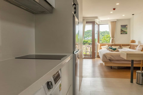 Kitchenette hob and fridge open onto the bright studio and balcony beyond