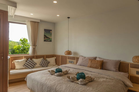 Queen bed beside the entry door with leafy treetop views through the window