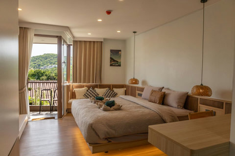 Bright studio bedroom with balcony access and lush tropical hillside views