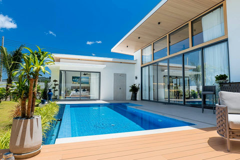 Modern bedroom suite with floor-to-ceiling glass doors opening directly to the pool.