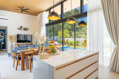 Luxurious indoor living & dining space with seamless pool and garden views.