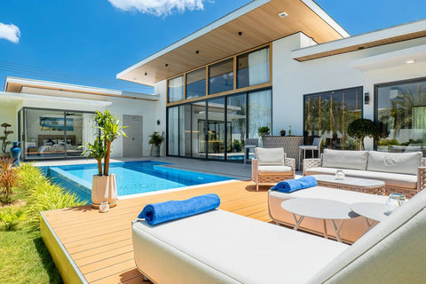 Bright and sunny pool deck with comfortable outdoor sofa and poolside seating.