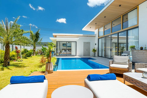 Spacious villa architecture surrounded by lush palm trees and private pool.