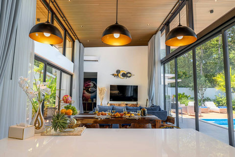 Bright open-plan living room with high ceilings, Smart TV, and lush green views.
