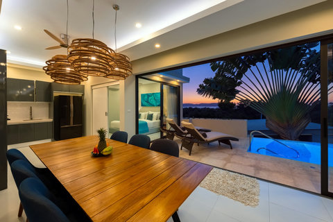 Gather around the wooden table as evening light streams across the kitchen and pool beyond.