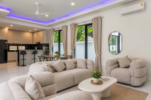 Bright open-plan living room with comfortable seating and direct connection to the kitchen and pool area.