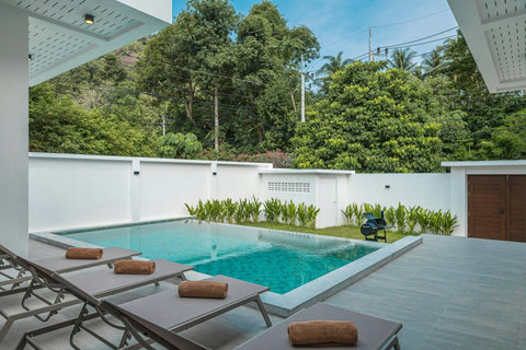 Private swimming pool with sun loungers and a peaceful tropical setting.