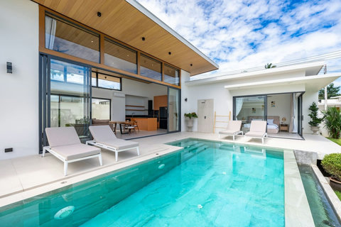 Daytime pool terrace with sun loungers, modern furniture and tropical garden views - Green Garden Villa
