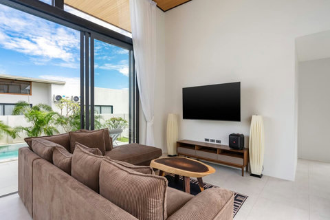 Living room with pool terrace views, comfortable sectional sofa and entertainment center - Green Garden Villa