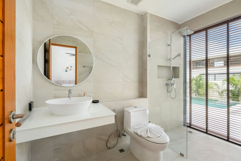 Modern bathroom with round mirror, walk-in shower and garden window views - Green Garden Villa