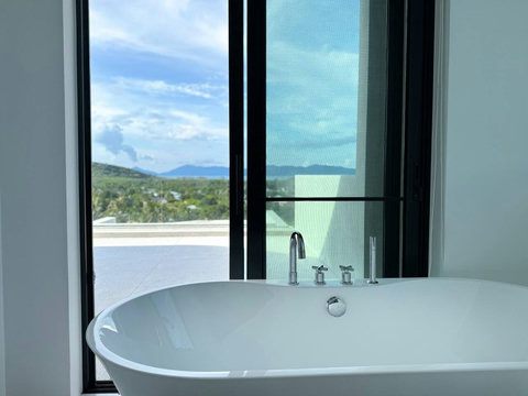 Relaxing freestanding bathtub beside the window with natural light and tropical