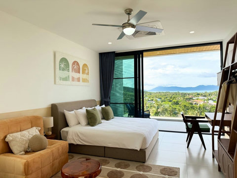 Spacious sea-view bedroom with comfortable seating and a dedicated workspace.
