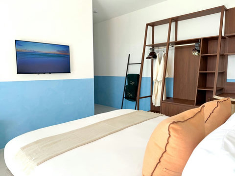 Comfortable bedroom with Smart TV, wardrobe and warm tropical styling.