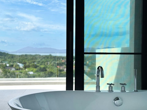 Relaxing freestanding bathtub beside the window with natural light and tropical