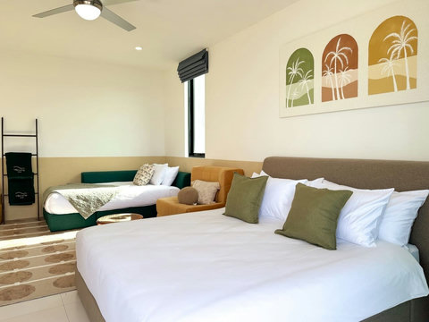 Spacious bedroom with comfortable sleeping areas, cozy seating and warm natural light.