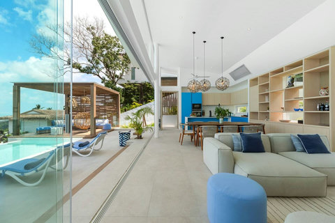 Sliding glass walls open the living room to the pool