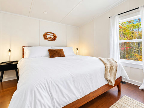 Rest easy in the comfortable king bedroom with crisp linens, warm touches, and a peaceful wooded feel.