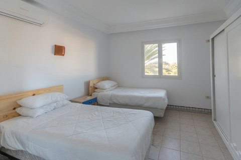 Chambre climatisée avec lit confortable, linge de qualité et espace de rangement. Ambiance paisible et déco inspirée de Djerba pour un repos total.