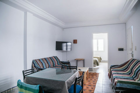Salon lumineux et climatisé avec canapé, table basse et TV.