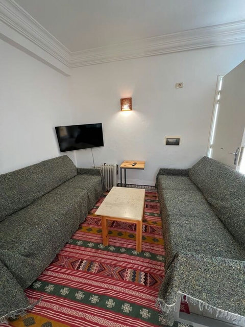 Salon lumineux et climatisé avec canapé, table basse et TV.