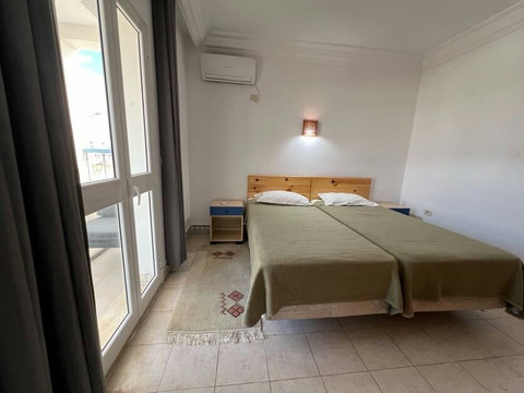 Chambre climatisée avec lit confortable, linge de qualité et espace de rangement. Ambiance paisible et déco inspirée de Djerba pour un repos total.