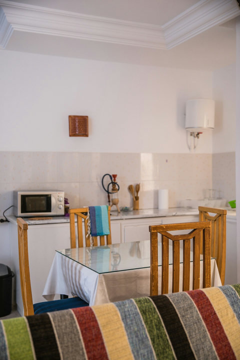 Kitchenette moderne et équipée avec réfrigérateur, plaques, micro-ondes et espace repas. Idéale pour cuisiner et partager vos repas dans une ambiance conviviale à Djerba.