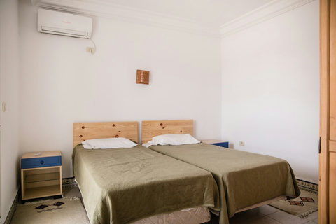 Une chambre avec deux lits simples séparés, une armoire et un miroir
