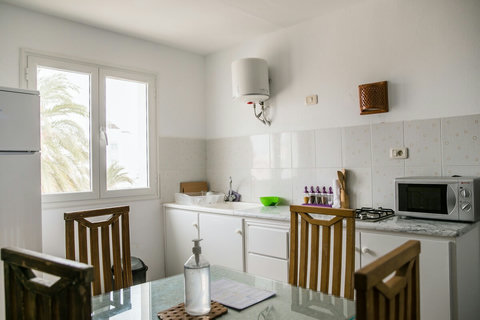Kitchenette moderne et équipée avec réfrigérateur, plaques, micro-ondes, vaisselle et espace repas. Idéale pour cuisiner et partager vos repas dans une ambiance conviviale à Djerba.