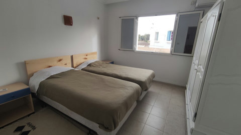 Chambre climatisée avec lit confortable, linge de qualité et espace de rangement. Ambiance paisible et déco inspirée de Djerba pour un repos total.