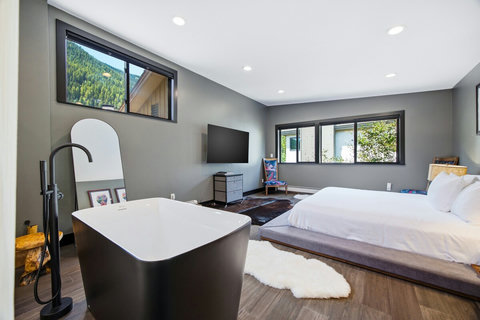 Modern bedroom retreat with soaking tub, mountain views, and bright natural light