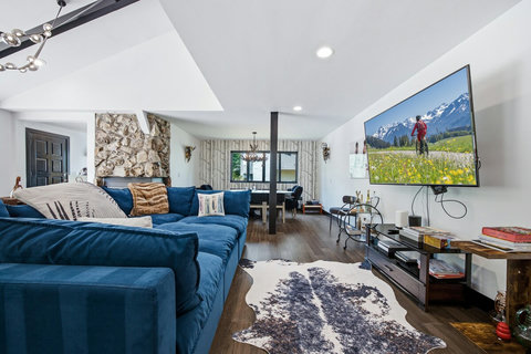 This living room has space for everyone with an oversized, cozy sectional, a wood burning stone fireplace, and big-screen TV
