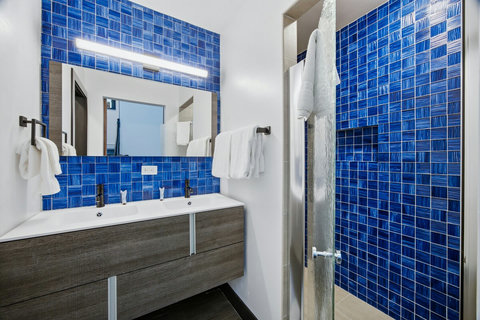 Contemporay custom bathroom with double vanity and bold blue tiled walk-in shower