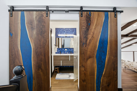 Custom live-edge barn doors open to a chic bath and loft bedroom