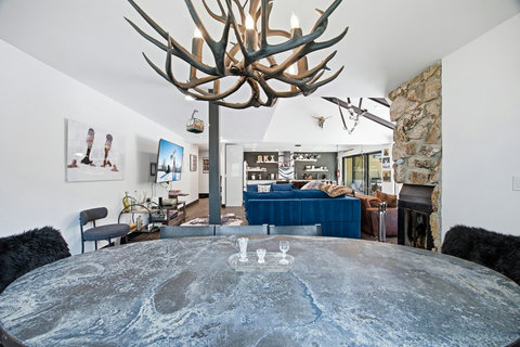 Mountain-chic dining and lounge with antler chandelier & stone fireplace