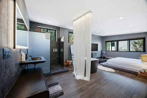 Modern spa-style suite with open shower, sleek design, and natural light. The en suite bathroom flows into the primary bedroom