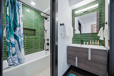 Modern bath with green tile, soaking tub, and sleek floating vanity