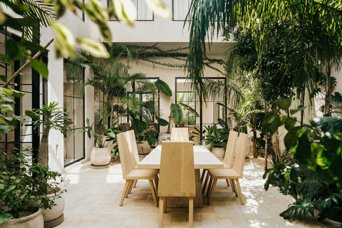 Sunlit courtyard dining area is surrounded by lush tropical plants