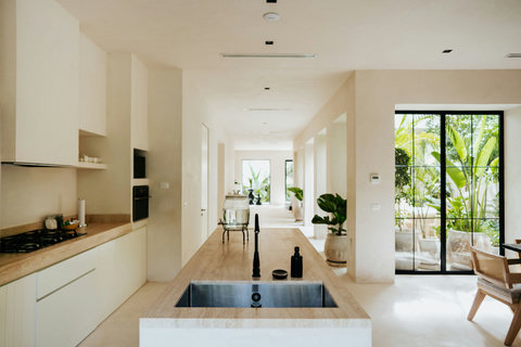 Open-concept kitchen with a sleek island and black-framed windows overlooking lush greenery
