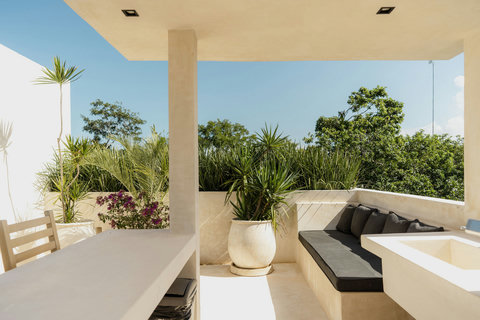Rooftop dining and lounge area with grill, bar seating, and greenery