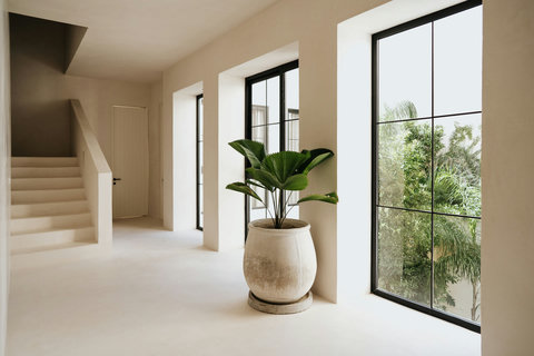 Minimalist hallway softened by greenery and an elegant staircase