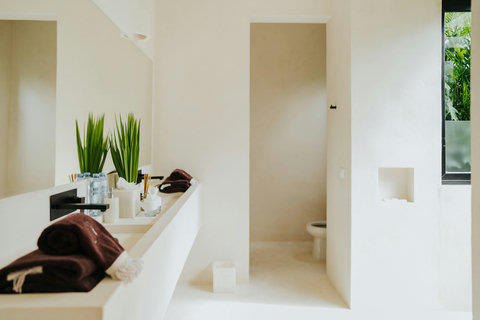 Light-filled modern bathroom with a wide sink, sleek mirror, and separate toilet