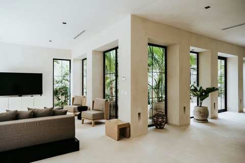 Contemporary living space featuring floor-to-ceiling windows, plants, and a serene garden view.