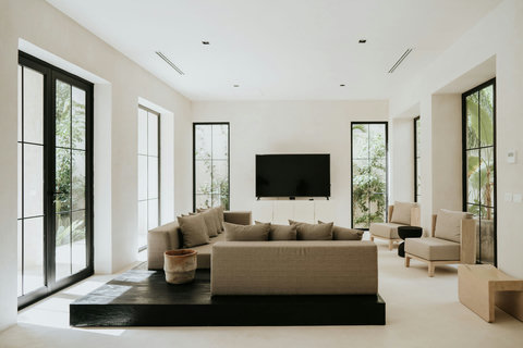 Modern living room with a minimalist palette, Smart TV, and floor-to-ceiling windows