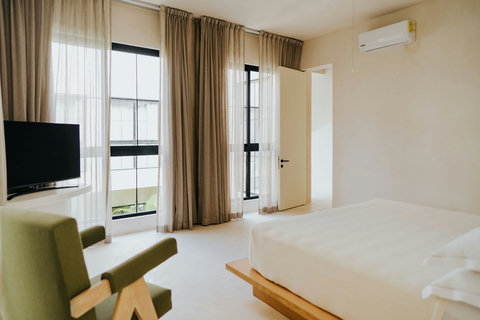 Sunlit bedroom with an armchair, air conditioning, and expansive floor-to-ceiling views